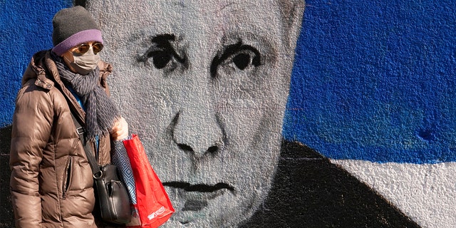 Egy nő elmegy egy Vlagyimir Putyin orosz elnököt ábrázoló falfestmény mellett a szerbiai Belgrádban, 2022. március 12-én, szombaton. 