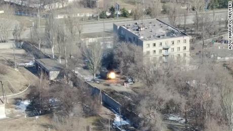 Ezen a drónfelvételekből készült képernyőképen egy katonai jármű látható, amely egy épület közelében lövéseket ad le.
