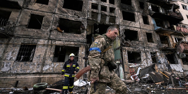 Ukrán katonák és tűzoltók egy bombatámadás után megsemmisült épületet vizsgálnak meg Kijevben, 2022. március 14-én, hétfőn. 