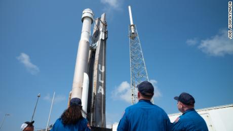 A NASA asztronautái, Sonny Williams, balra, Barry  Butch & quot;  Willmore, középen, és Mike Finky, jobb, egy United Launch Alliance Atlas V rakétát néznek a Boeing járművével.  A SpaceX CST-100 Starliner a fedélzetén a függőleges integrációs létesítménytől a 41-es Space Launch Complex indítóállásáig az Orbital Flight Test 2 (OFT-2) küldetése előtt, 2022. május 18-án, szerdán, a floridai Cape Canaveral űrállomáson. 