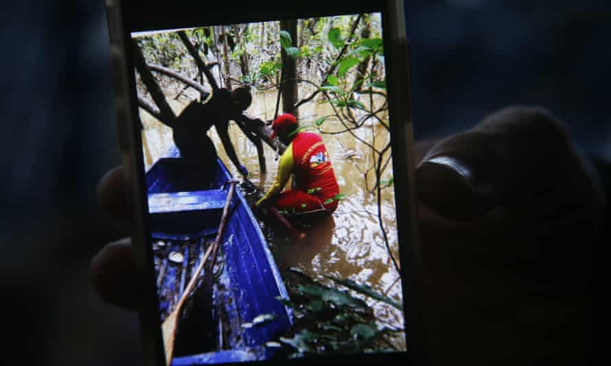 Egy tűzoltó a kezében tart egy telefont, amelyen a képen látható a pillanat, amikor egy hátizsákot találtak Bruno Pereira őslakos szakértő és Dom Phillips brit újságíró után.