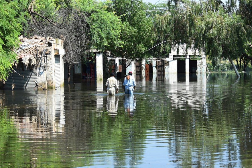 A lakók az árvízben gázolnak otthonaik közelében a heves monszun esőzések után.
