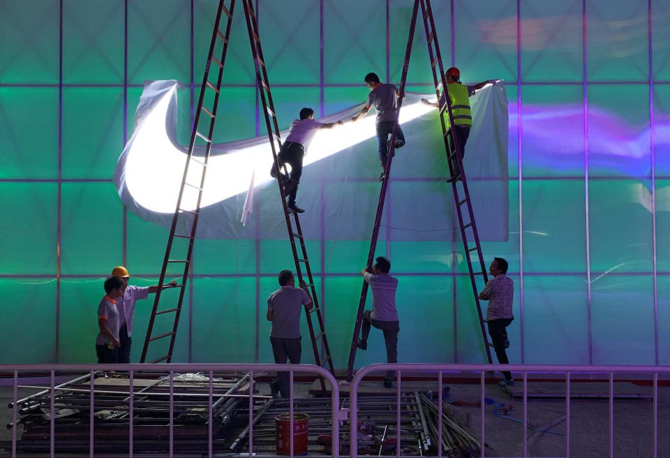A munkások Nike logós lámpát szerelnek fel a pekingi Wukesong Aréna előtt 2019. augusztus 28-án. A fénykép 2019. augusztus 28-án készült. REUTERS / Tingshu Wang
