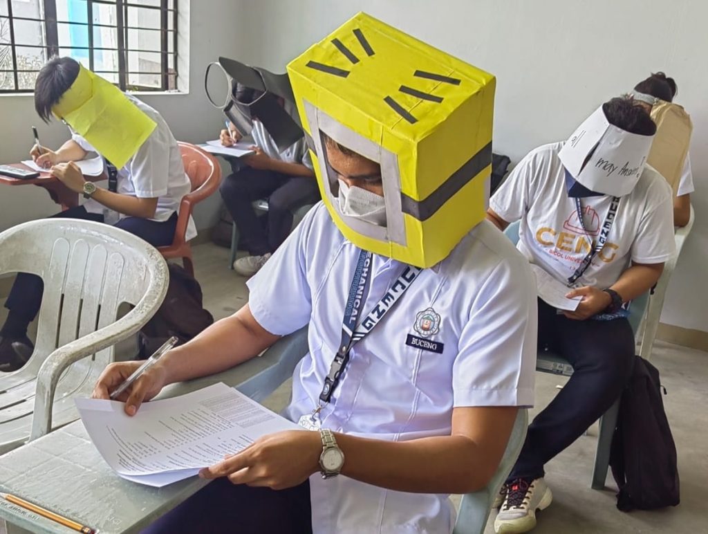 Vannak képek a filippínó diákokról, akik csalás elleni kalapot viselnek