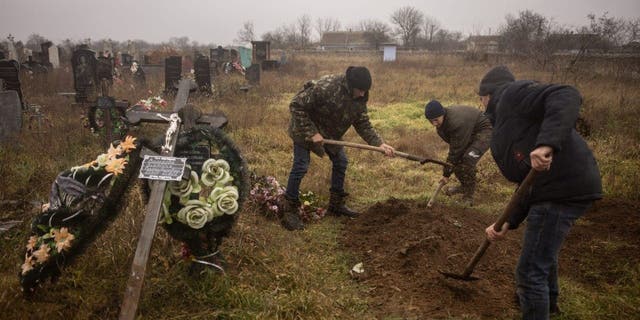 Ukrán lakosok és tisztviselők exhumálják egy 16 éves lány és hét másik férfi holttestét, akiket az orosz erők megöltek és eltemettek Pravdin városában, Herszon külvárosában 2022. november 29-én.